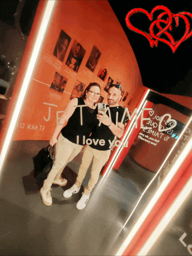 a man and a woman are taking a picture in front of a mirror that says i love you