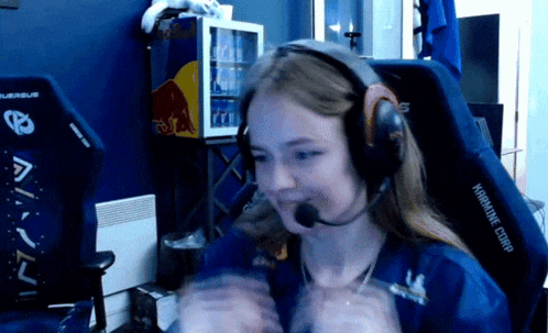 a woman wearing headphones and a microphone is sitting in a chair with a red bull cooler behind her
