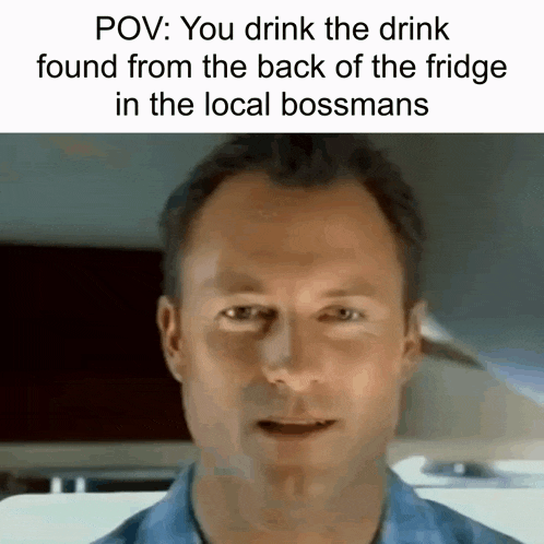 a man in a blue shirt is drinking a drink from the back of the fridge .