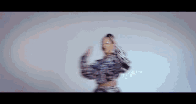 a woman in a zebra print crop top is dancing in front of a white wall .