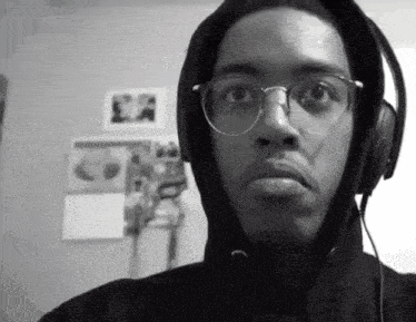 a black and white photo of a man wearing headphones and a hoodie