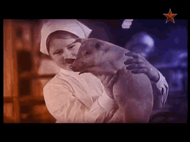 a woman is holding a pig in her arms with a red star in the background