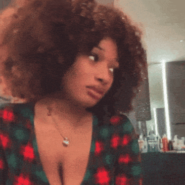 a woman with curly hair is wearing a necklace with a heart pendant