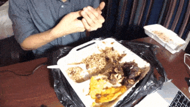 a man is sitting at a table with a container of food on it