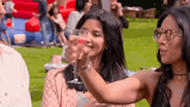 a woman is holding a glass of wine in her hand while sitting next to another woman .
