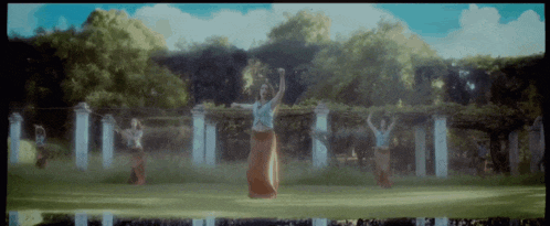 a group of women dancing in a park with trees in the background