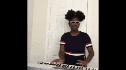 a girl wearing sunglasses is playing a keyboard in front of a door