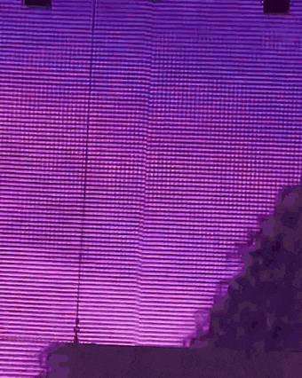a purple light is shining on a building with a purple sky in the background .