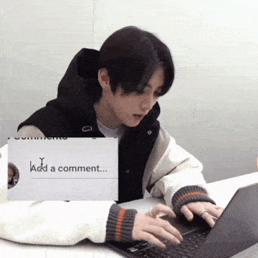 a man is typing on a laptop with a sign that says add a comment
