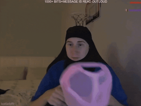 a person wearing a blue shirt and a black head scarf with 1000+ bits = message is read outloud on the bottom