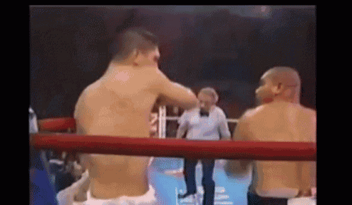 two men are fighting in a boxing ring while a referee watches .