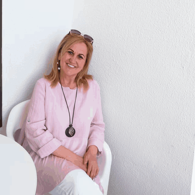 a woman wearing sunglasses and a pink shirt is sitting in a chair