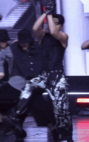 a man wearing a black tank top and silver pants is dancing on a stage