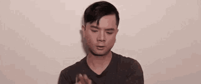 a man in a gray shirt is holding a pen in his hand and making a funny face .