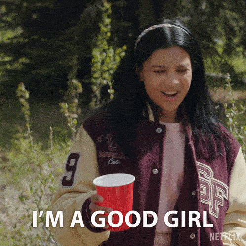 a girl in a varsity jacket is holding a red cup and says i 'm a good girl