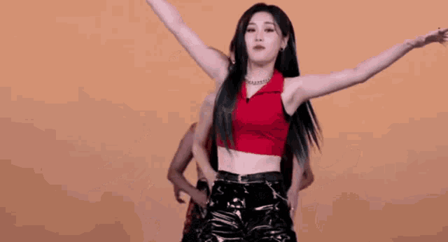 a woman in a red crop top is dancing with her arms outstretched in front of a group of women .