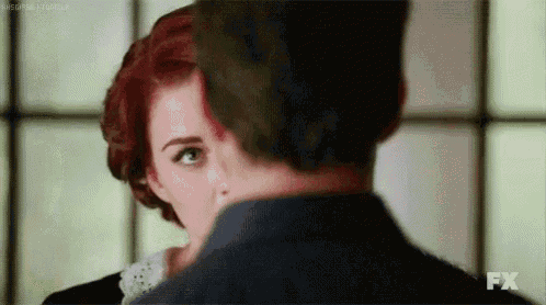 a man and a woman are looking at each other . the woman has red hair and the man has green hair .