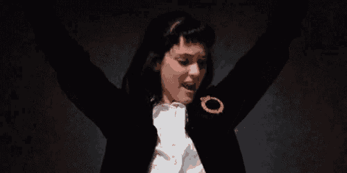 a woman in a tuxedo is dancing in a dark room .