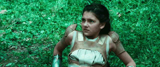 a young girl is sitting in the grass wearing a costume .