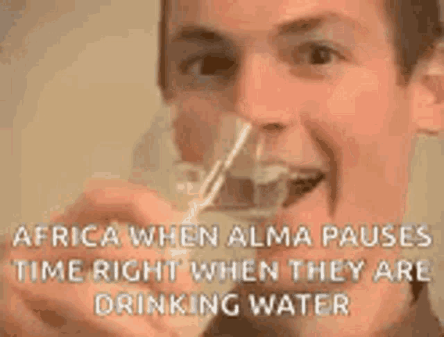 a man is smiling while drinking water from a bottle .