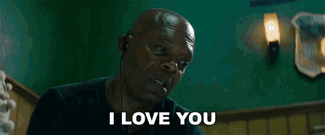 a bald man wearing ear buds says " i love you "