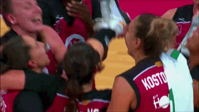 a group of basketball players are huddled together and one of them has kosto on her back