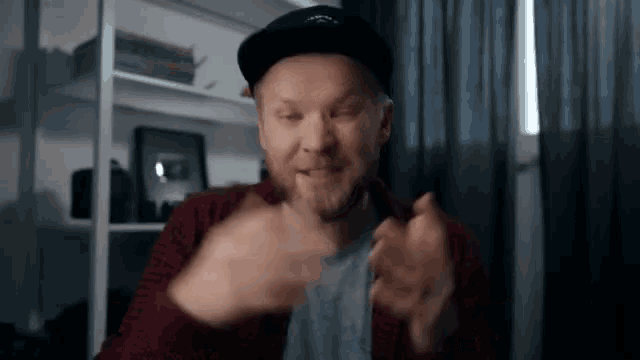a man in a hat is making a funny face while sitting in front of a computer screen .