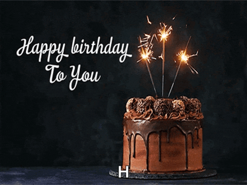 a chocolate birthday cake with sparklers on it and the words happy birthday to you