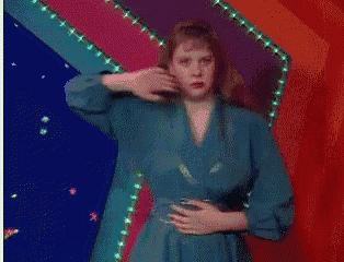 a woman in a blue dress is holding her stomach in front of a red and blue background .