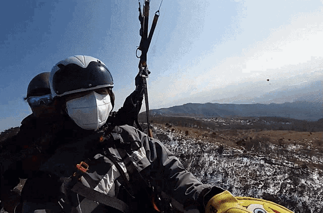 a person wearing a mask and a helmet is holding a parachute