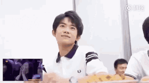 a young man is sitting at a table with a pizza in front of him .