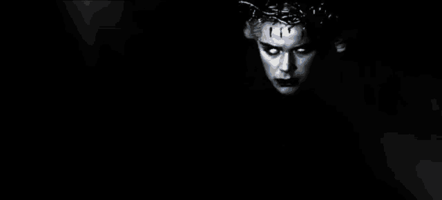 a woman in a black leather jacket is sitting in a chair in the dark .