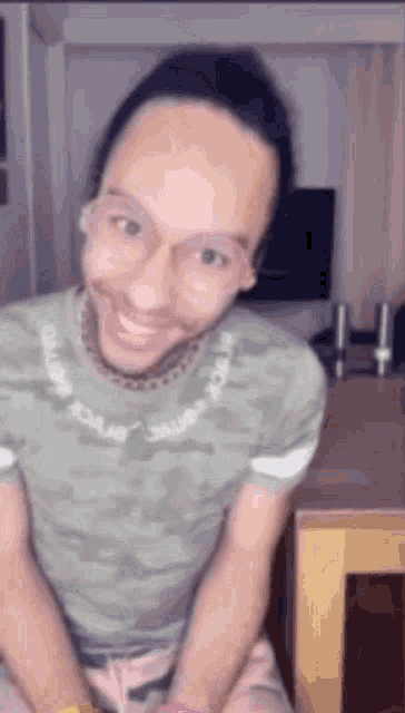 a man wearing glasses and a green shirt is smiling