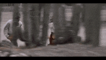 a man in a white shirt is walking through a fence .