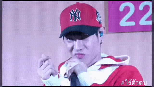 a man wearing a red new york yankees hat and a red hoodie is making a funny face .