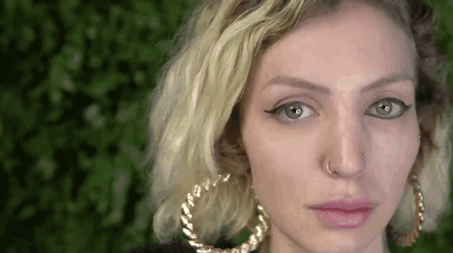 a close up of a woman 's face with a nose ring and earrings .
