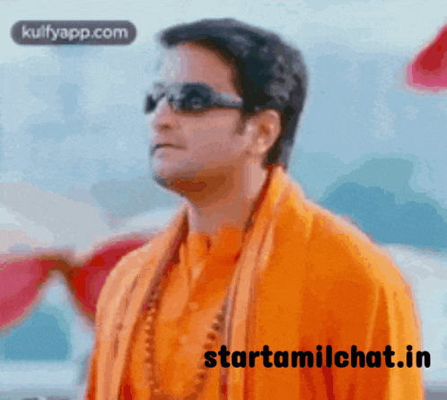 a man wearing sunglasses and an orange shirt is standing in front of a starttamilchat.in website