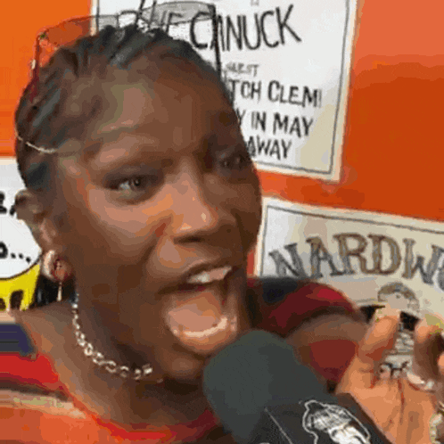 a woman is screaming into a microphone in front of a sign that says nardw