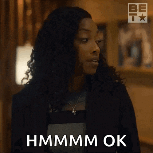 a woman with curly hair is making a face and says hmmm ok