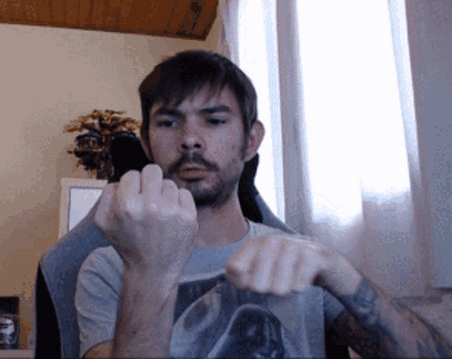 a man with a beard and a tattoo on his arm shows his middle finger