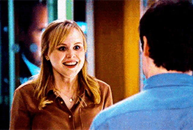 a woman in a brown shirt smiles at a man in a blue shirt