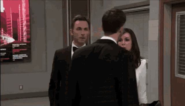 a man in a tuxedo stands next to a woman in a white dress