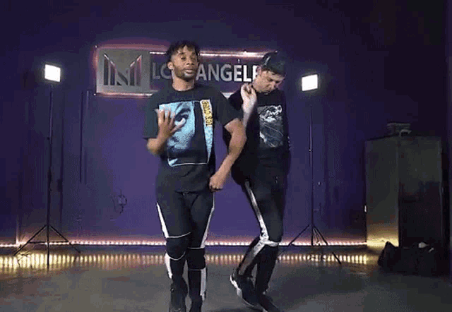 two men are dancing in front of a sign that says angels