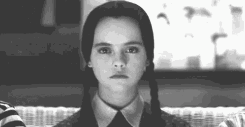 a black and white photo of a girl with pigtails making a face .