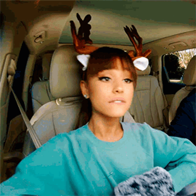 a woman in a car wearing reindeer antlers