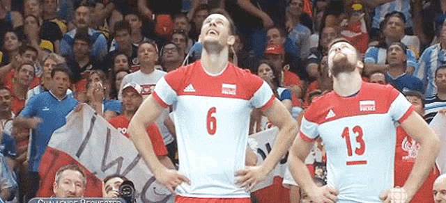 two volleyball players are standing in front of a crowd and one has the number 13 on his jersey