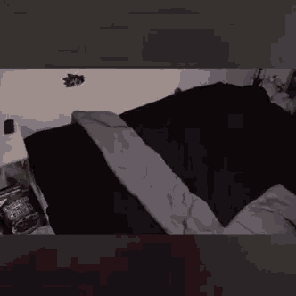 a bed with a black comforter and a gray comforter is laying on a bed in a bedroom .