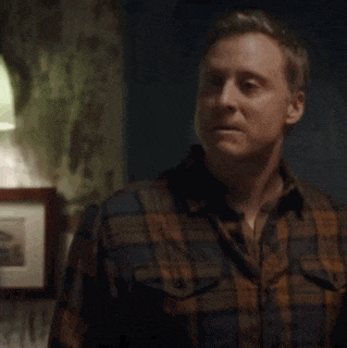a man in a plaid shirt is sitting in a dark room