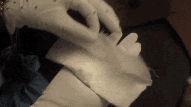 a person wearing white gloves is holding a piece of fabric