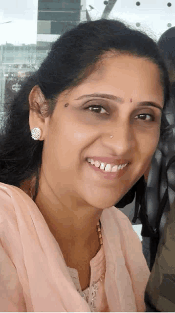 a woman with a nose ring is smiling and wearing earrings